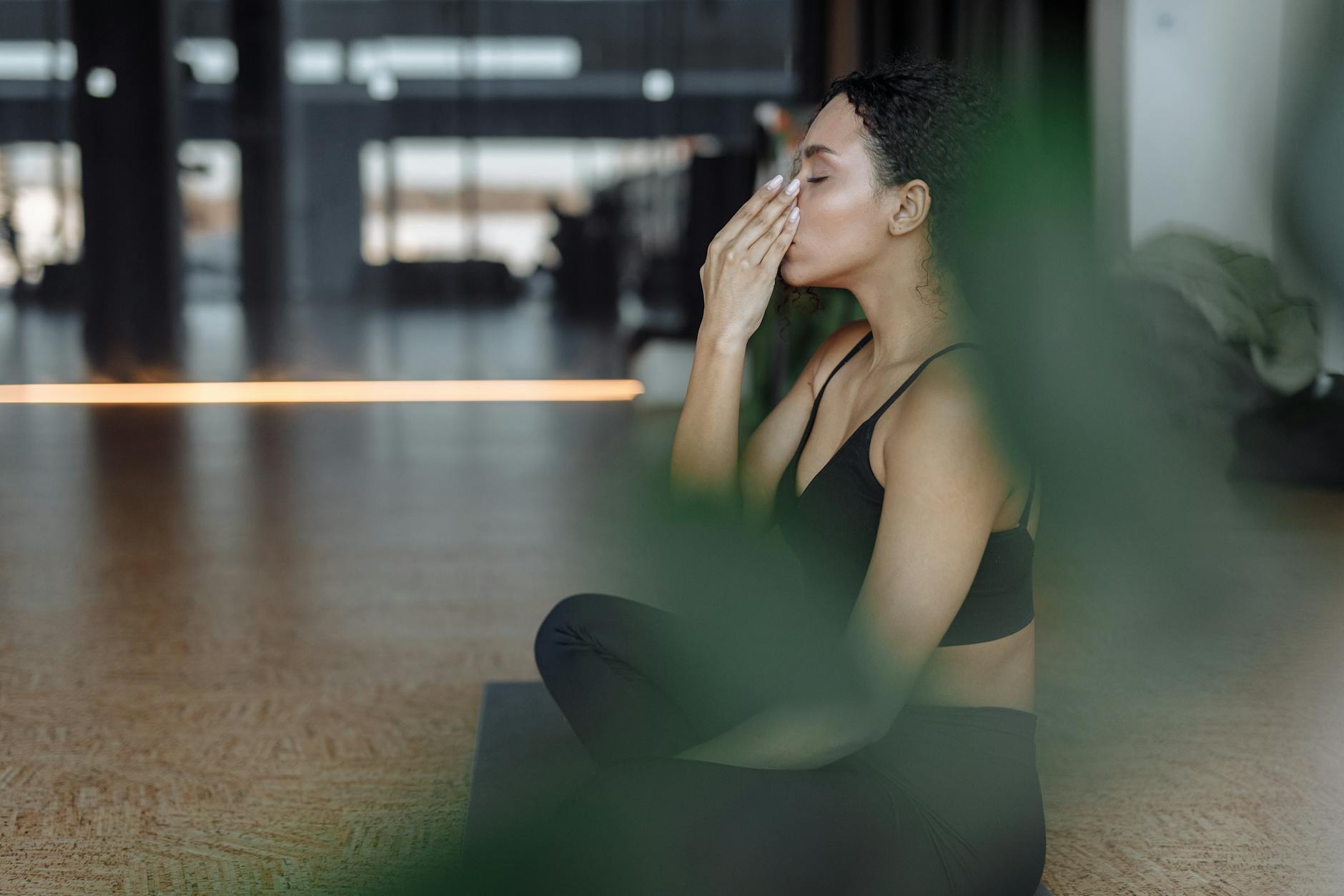 woman in black active wear concentrating while sitting on a yoga mat