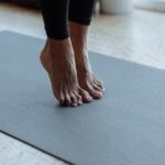 person in black pants on black yoga mat