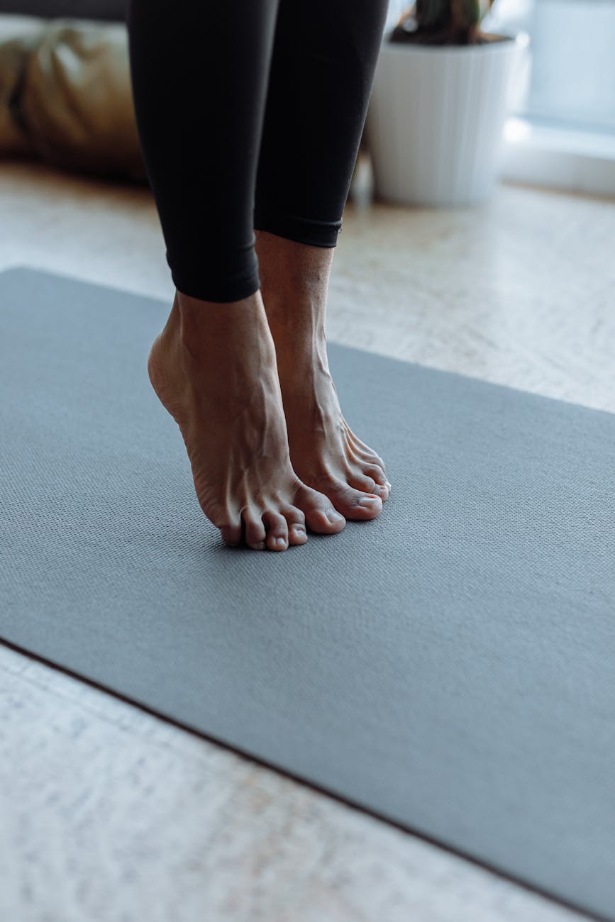 person in black pants on black yoga mat